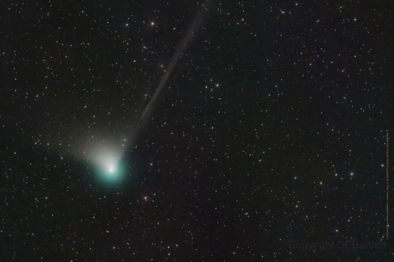 A green comet with a fuzzy table is visible against a background of stars